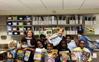 Kids with books standing excitedly.